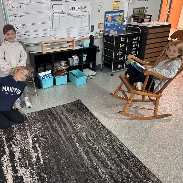 Image description for accessibility:  students on carpet and in rocking chair
