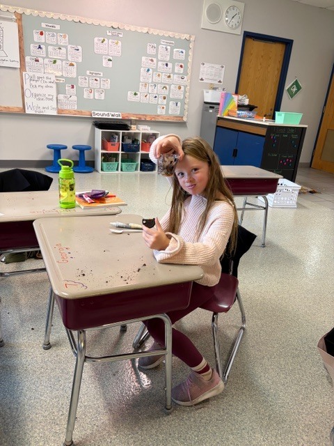 Image Description for accessibility:  Student eating snack at her desk