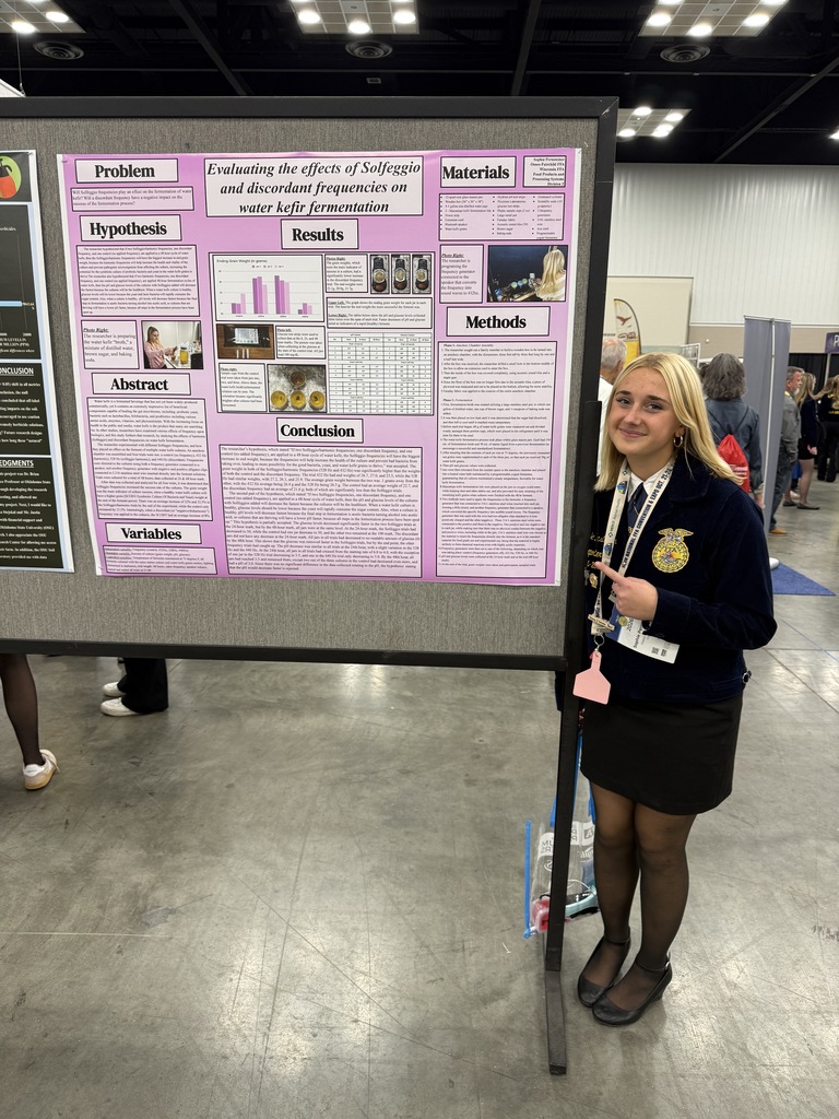 Image Description for accessibility:   Sophie standing next to her display board