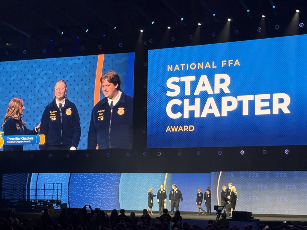 Image Description for accessibility:  Students seen on stage and on the Jumbo Screen accepting a National FFA Star Chapter Award