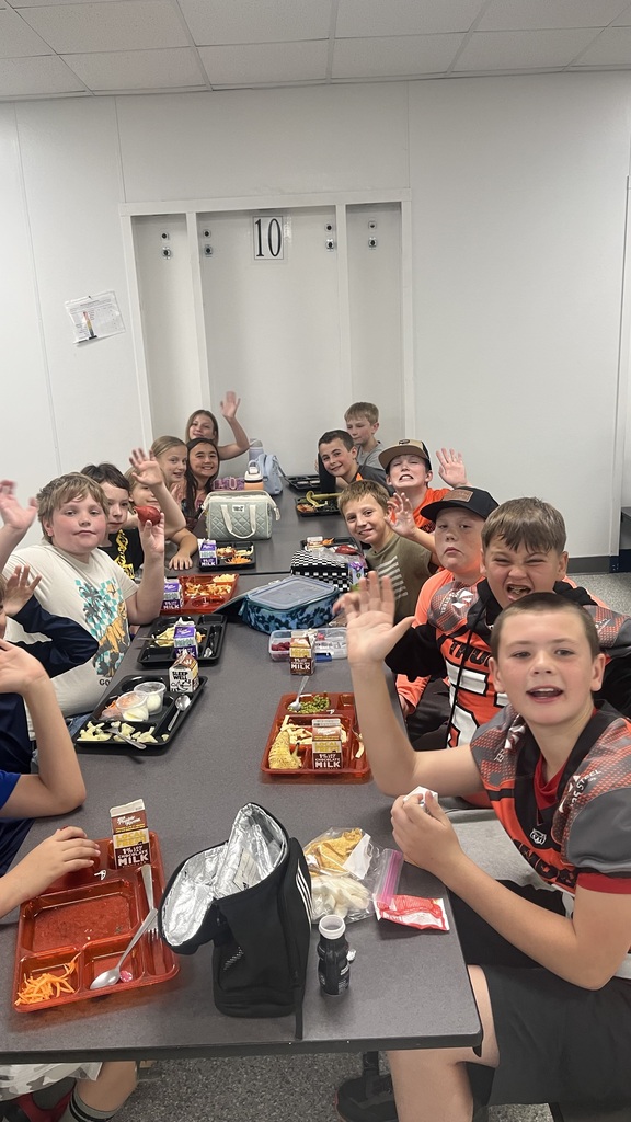 Image description for accessibility:   Students and law enforcement officers in school lunchroom
