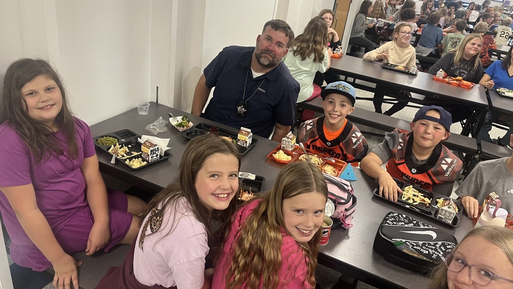 Image description for accessibility:   Students and law enforcement officers in school lunchroom