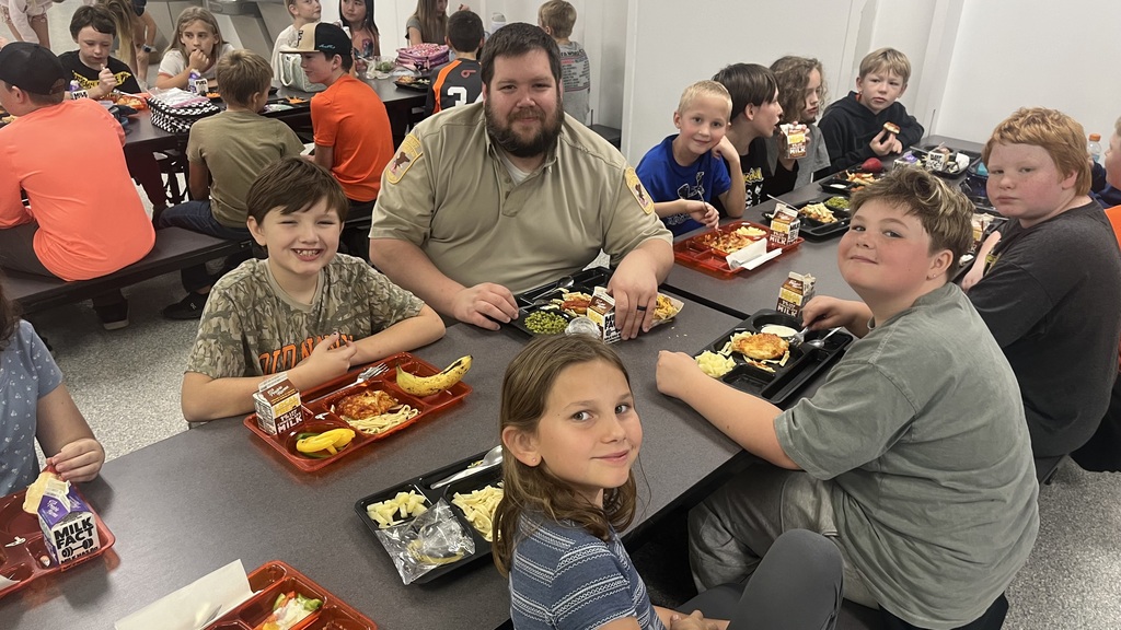 Image description for accessibility:   Students and law enforcement officers in school lunchroom