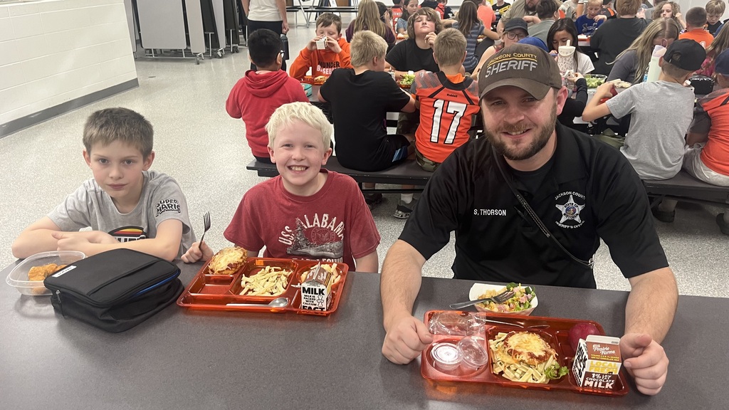 Image description for accessibility:   Students and law enforcement officers in school lunchroom