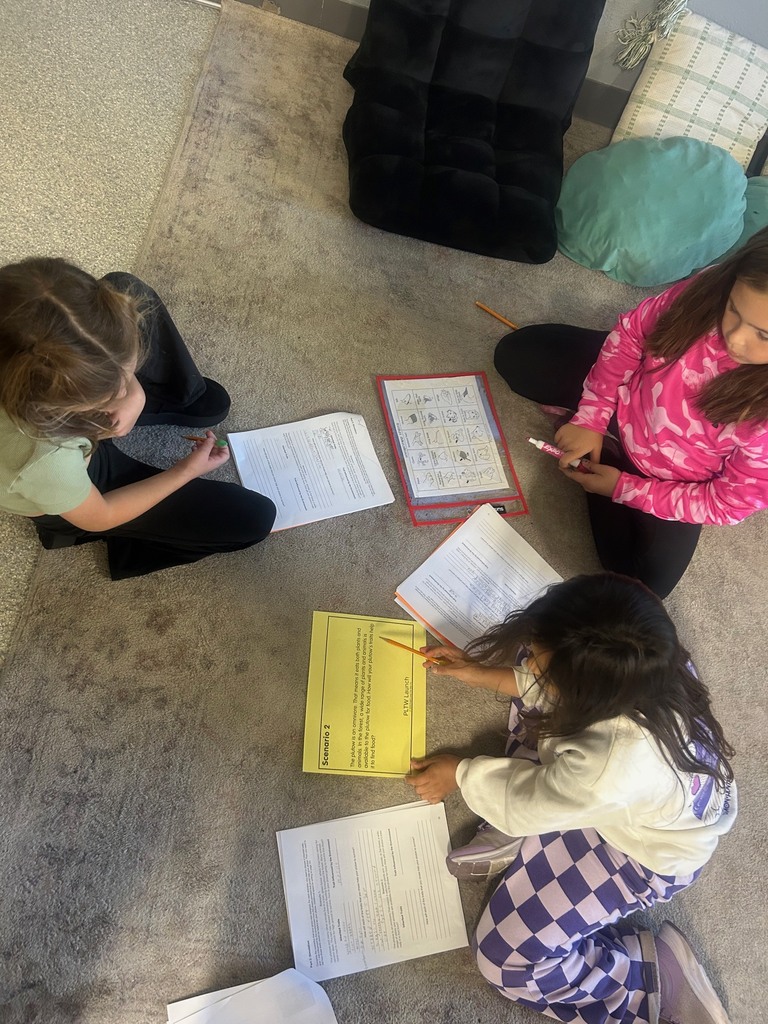 Image description for accessibility:  three students sitting on the floor working on school work