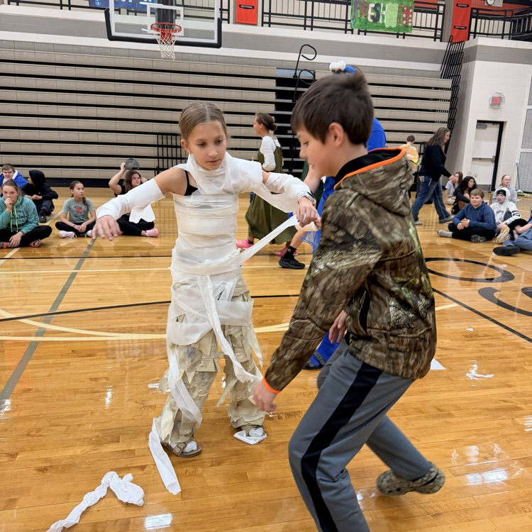 Image description for accessibility, one student wrapping toilet paper around another student in a gym