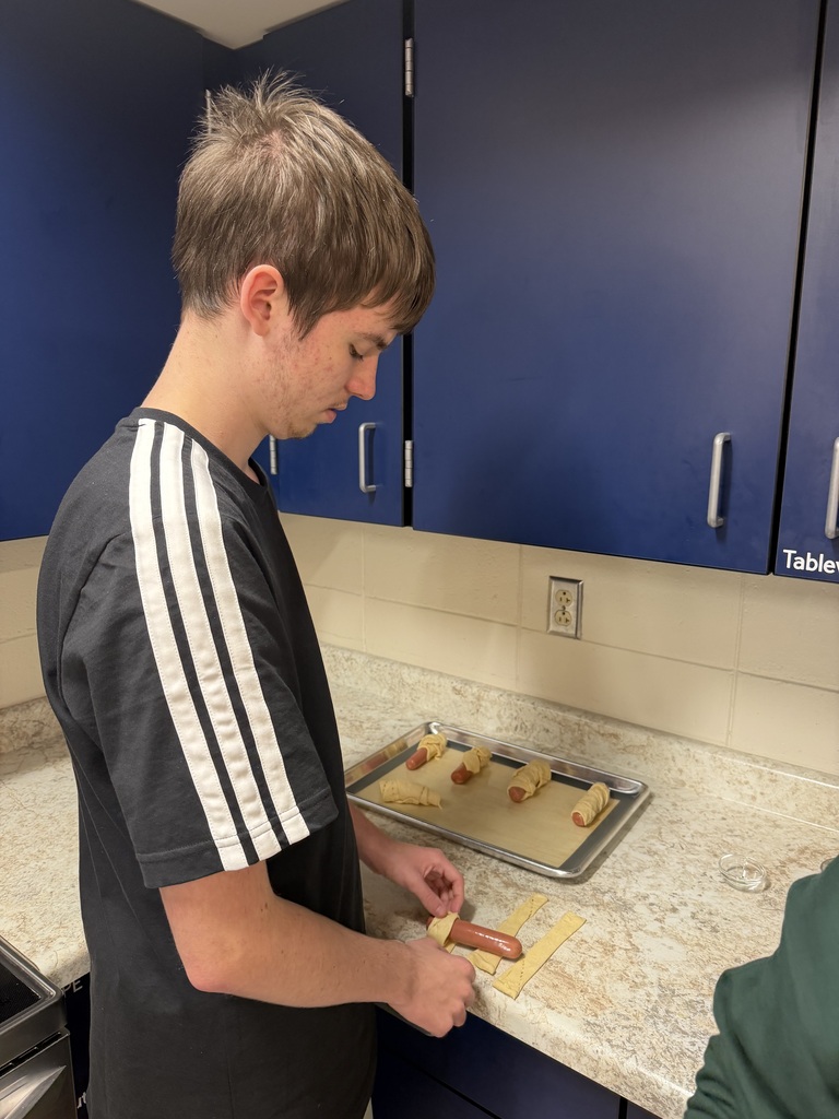 Image Description for accessibility: Student wrapping hot dog in dough