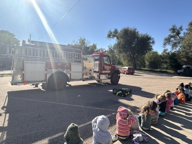 Children sitting in front of fire truck waiting for presentation to begin.