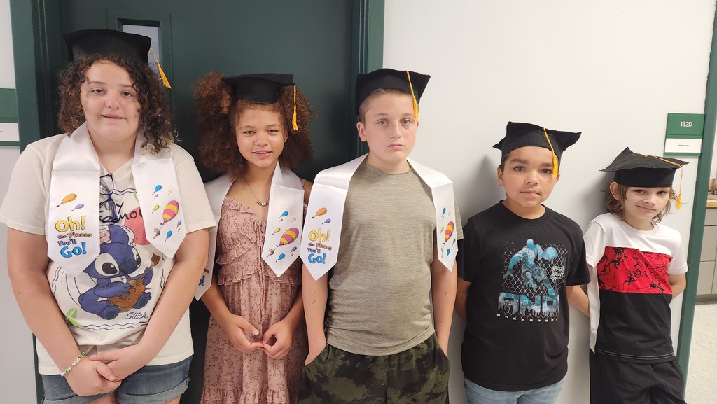 5 students posing inside with graduation caps