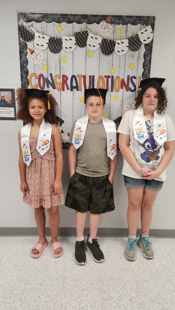 3 students posing inside with their graduation caps