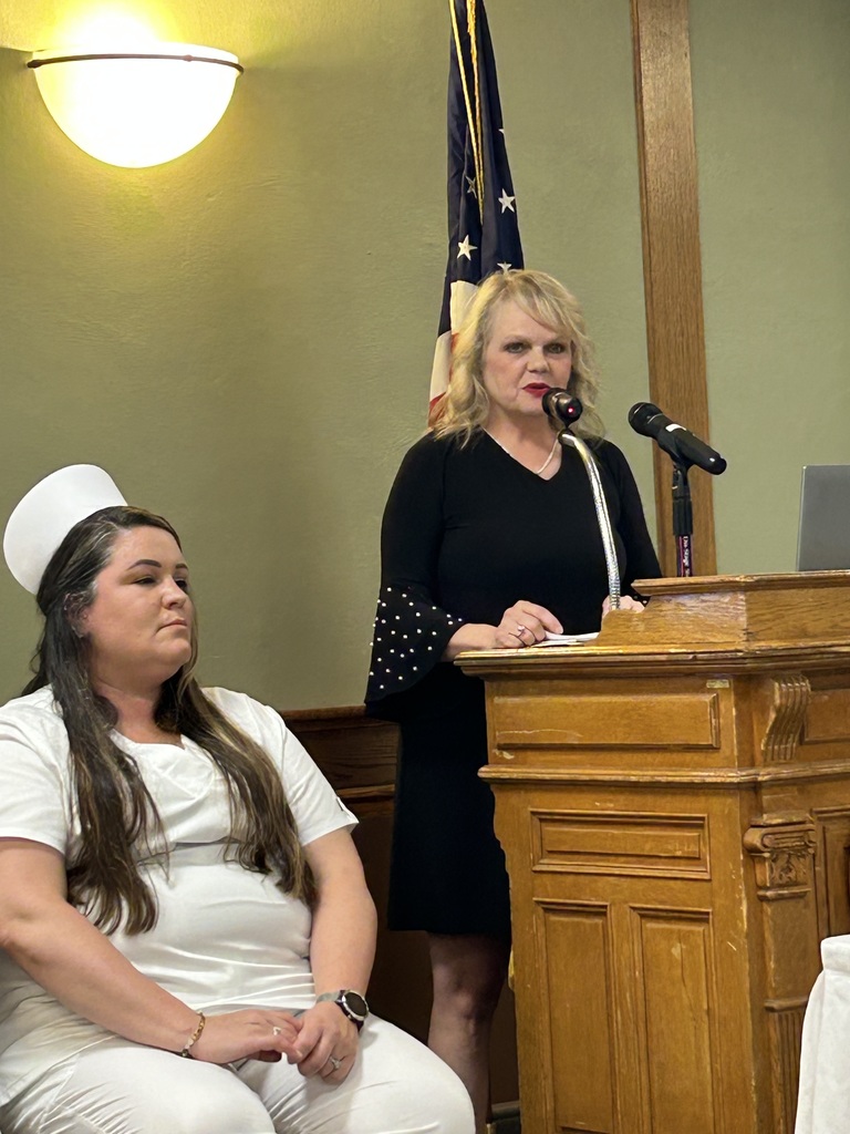 Student on stage with instructor speaking at podium