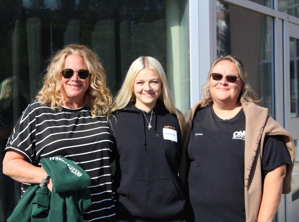Three staff members posing together outside