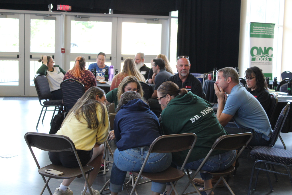 Group of employees huddled in teams around tables