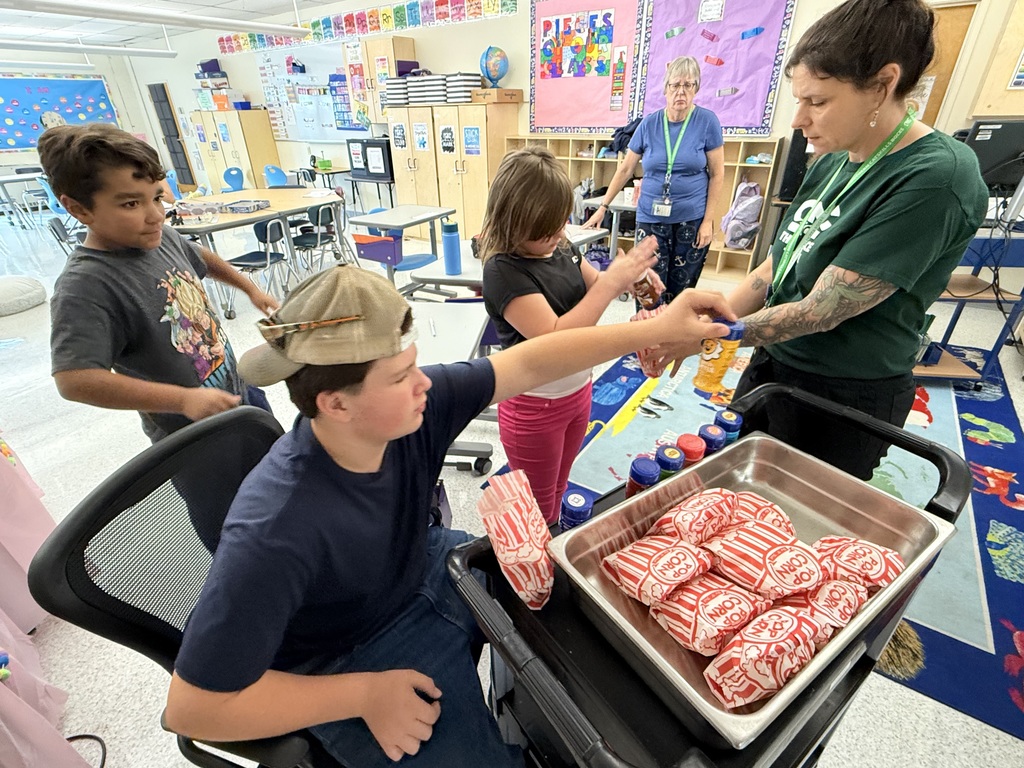 Three students receiving popcorn from staff.
