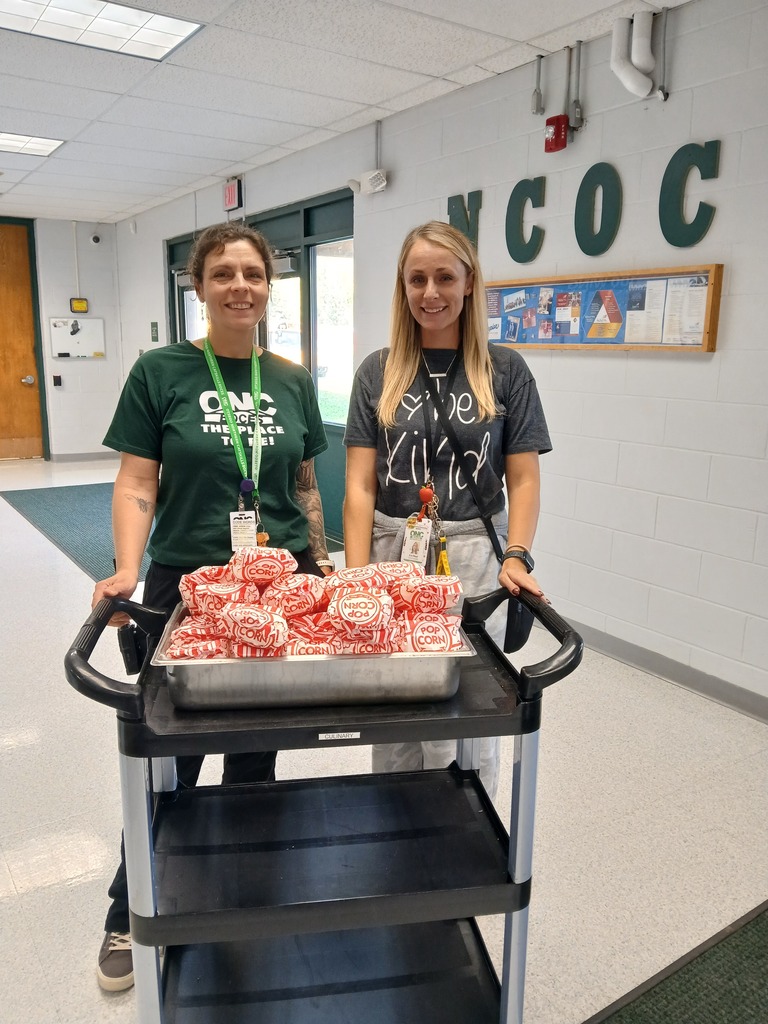 Two staff members delivering popcorn on a cart.