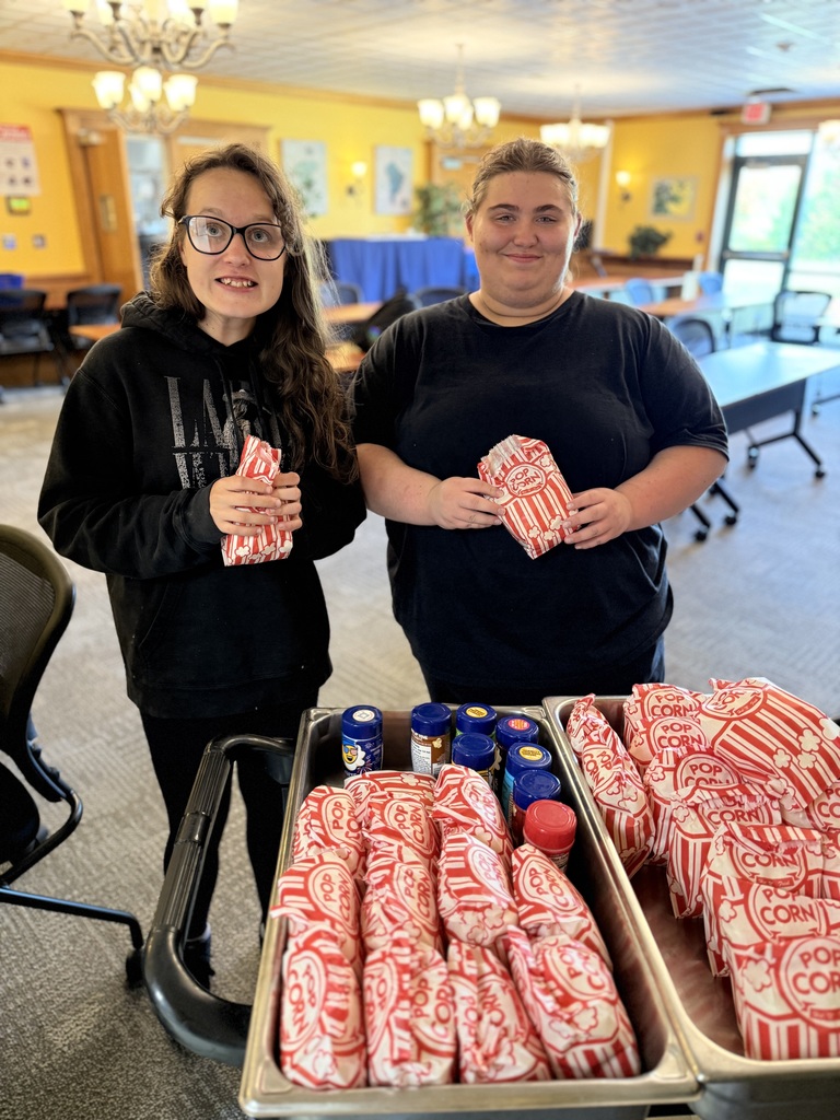 Two students with bags of popcorn and seasonings.