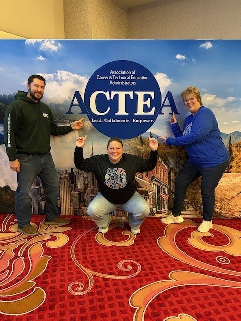 Jesse Bright, Tera Talbot, and April Erkson in front of the ACTEA sign