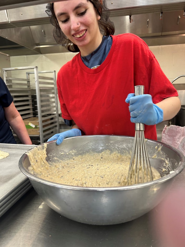 Student in a kitchen mixing a large bowl of food