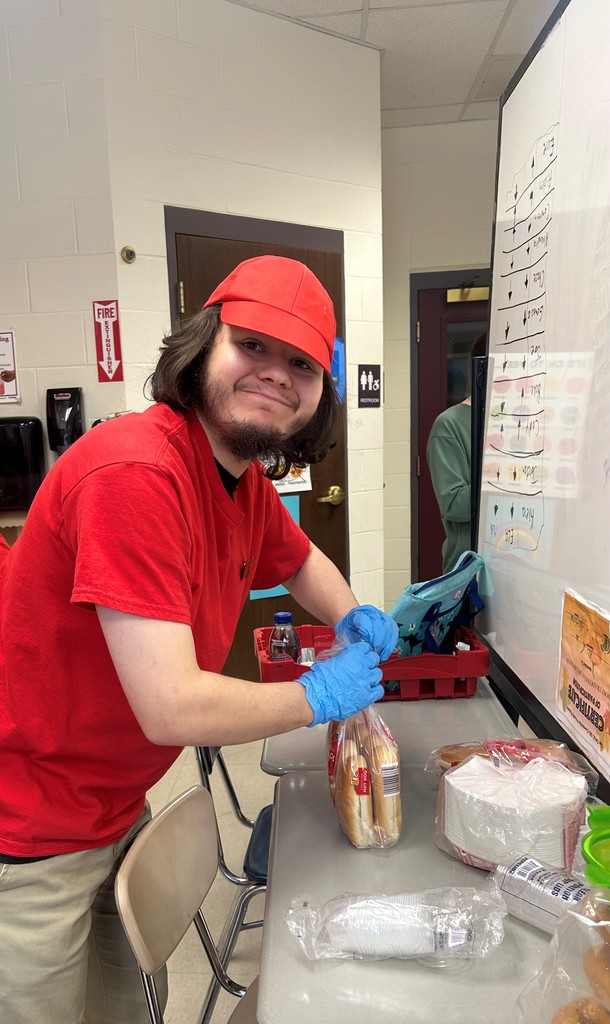 Student working in school cafe, opening hot dog rolls