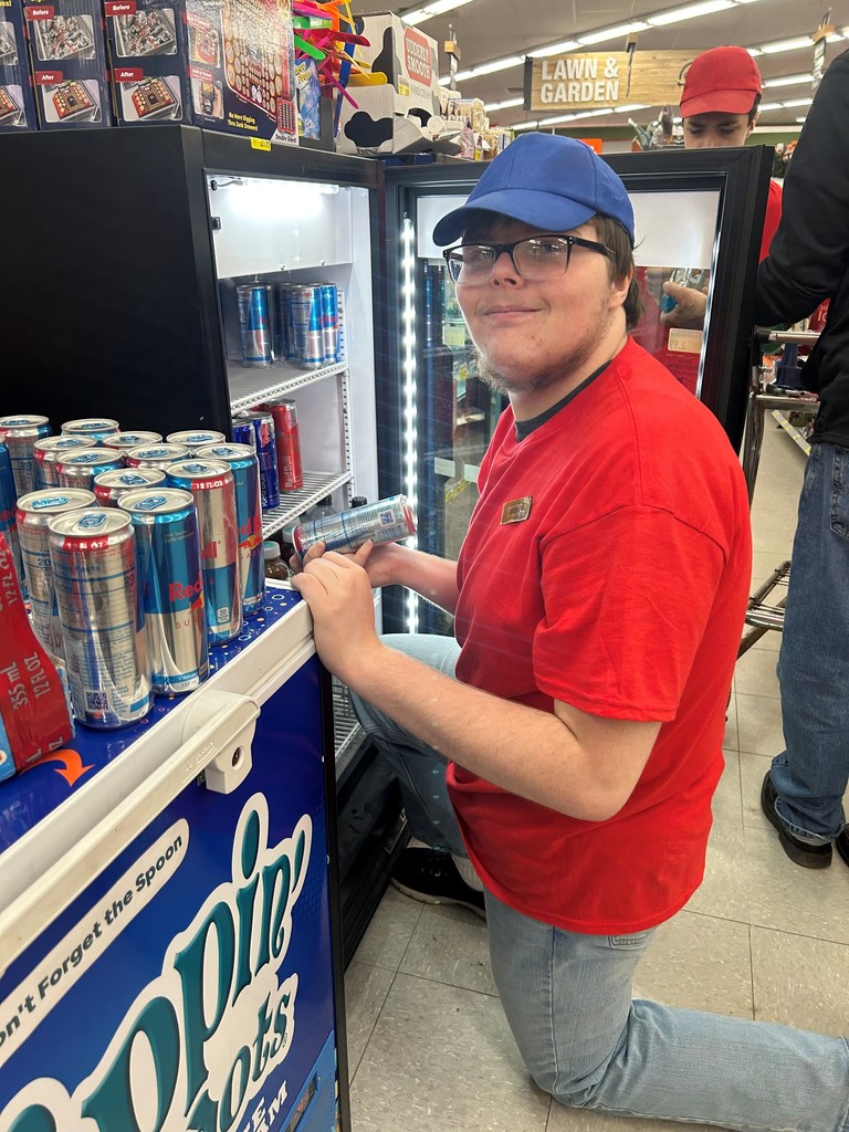 Student working in a store holding drink can