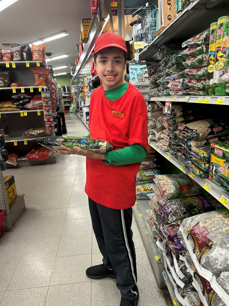 Student working in a store holding a bag of feed