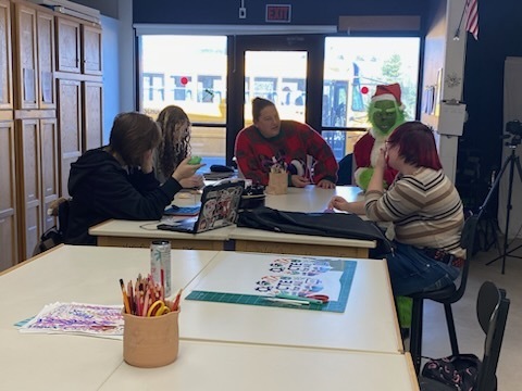 The Grinch with staff members sitting at a table