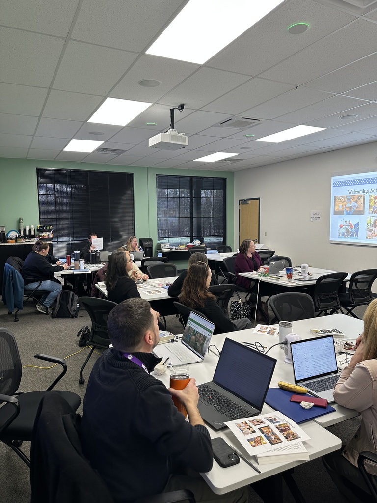An Instructional Support Staff member leading a training with a group of people sitting at tables.