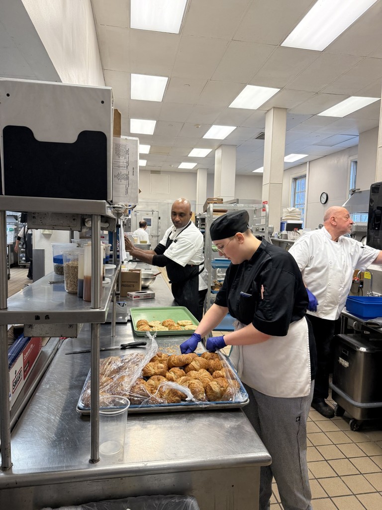 Student in a restaurant kitchen with two others workers