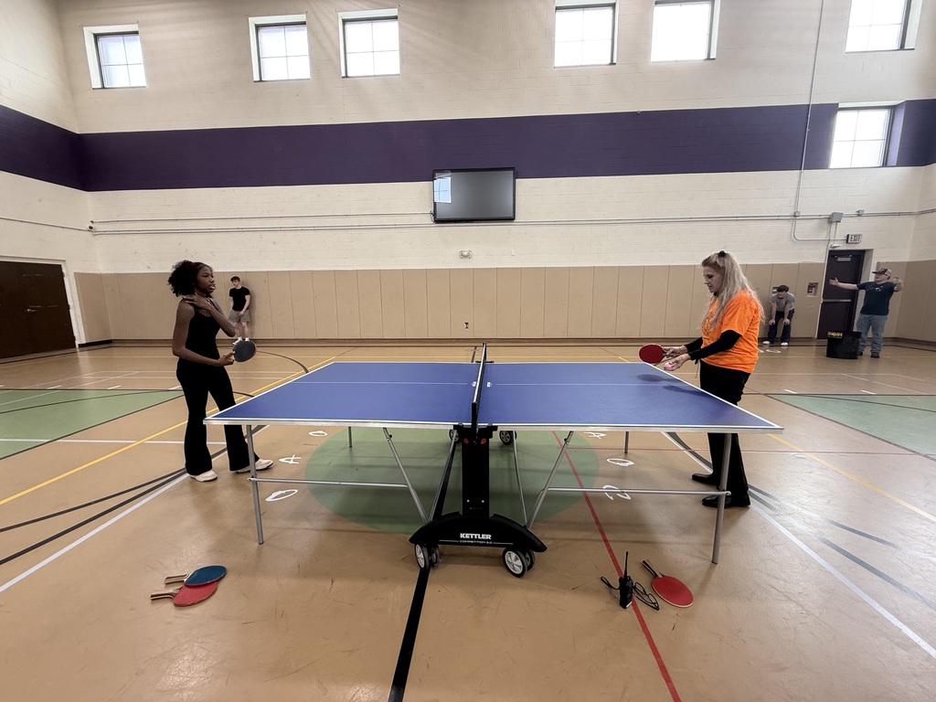 Two students playing ping pong in the gym