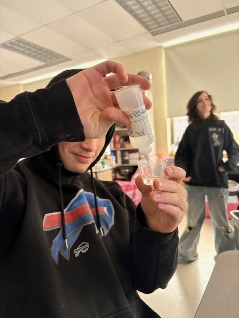Student putting a liquid into a cup
