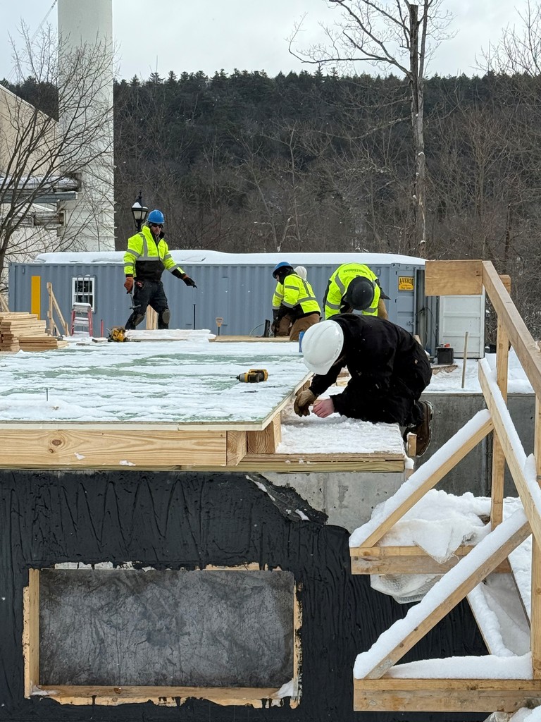 5 eople working on building a structure in hard hats and snow