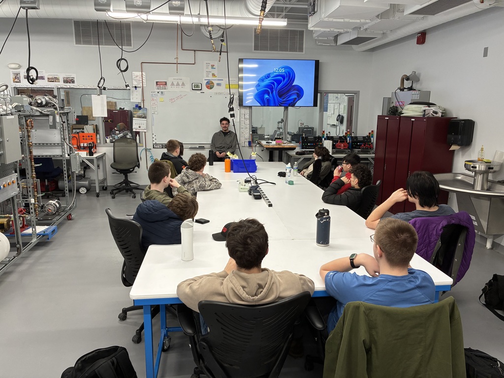 Alumnus sitting at the head of a table with current students sitting around the table