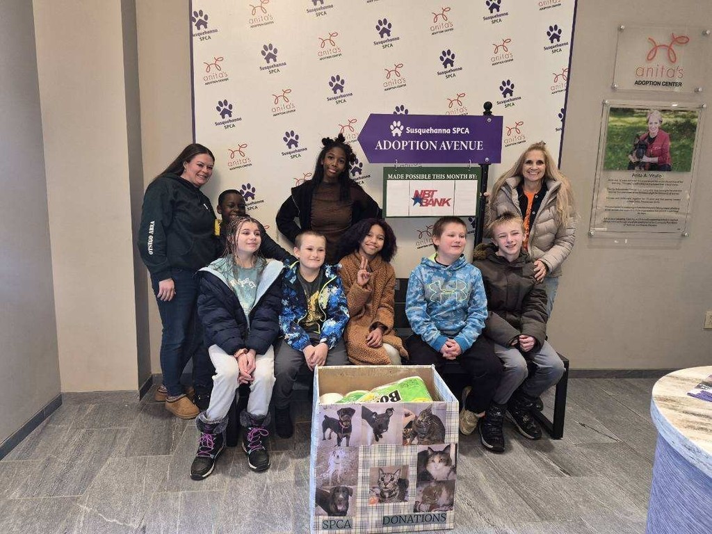 A group of students and staff posing with the box of donations at the animal shelter.