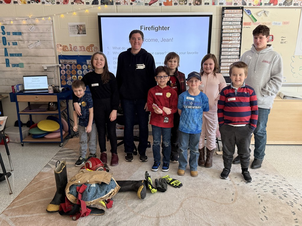 Group of elementary students and teacher with guest speaker, Jean, Firefighter