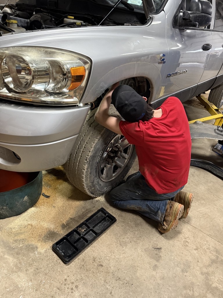 A student working near a wheel of a truck.
