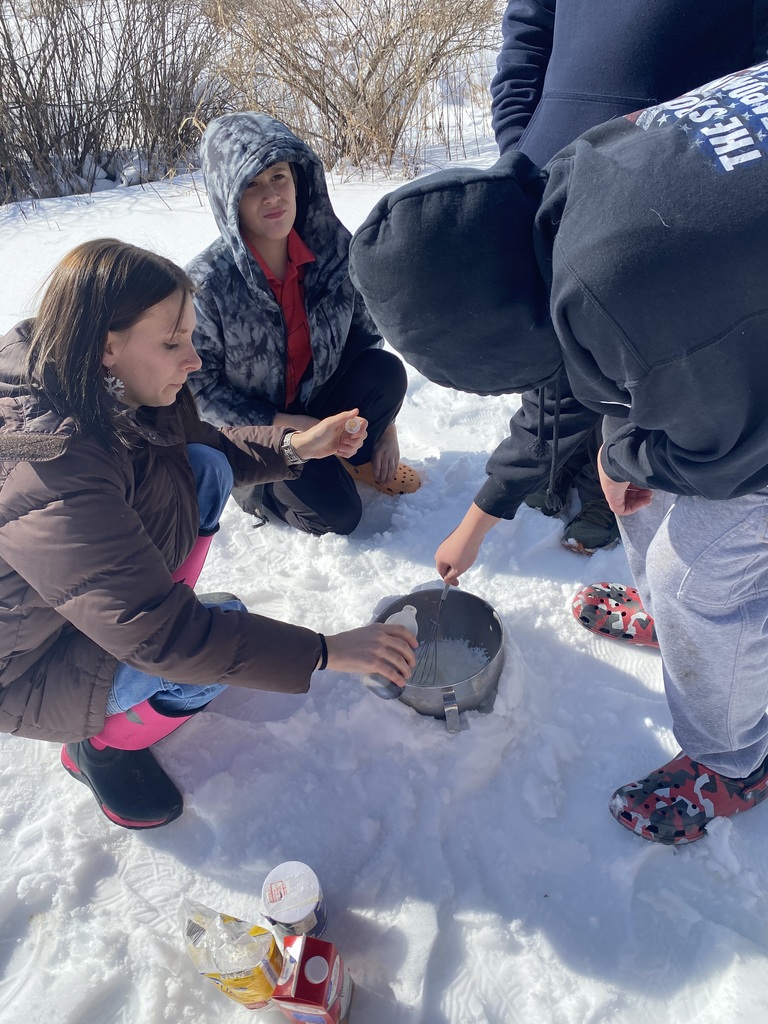 Three students and a staff member outside mixing snow and ingredients in a bowl