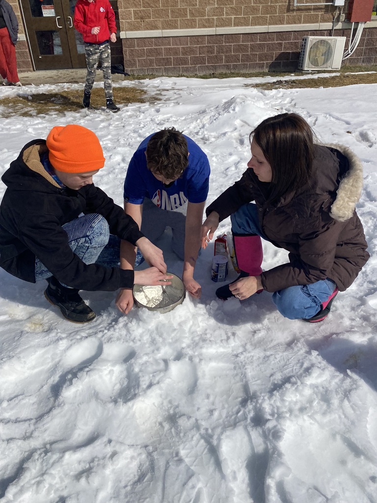 Staff member and two students mixing snow and other ingredients in a bowl outside