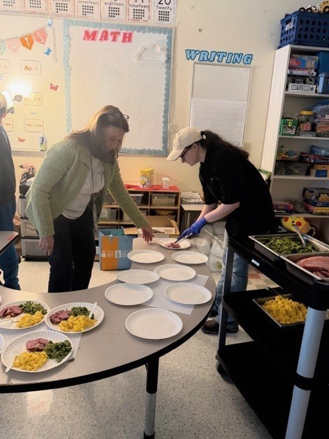 Culinary student and staff member plating green eggs and ham for students