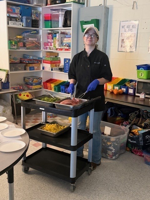 Culinary student holding a fork and knife cutting ham