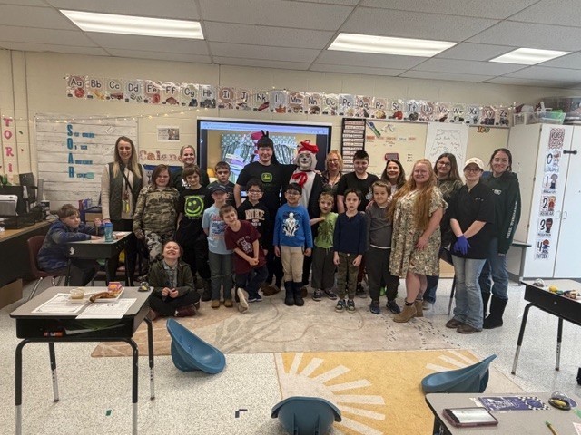 Group of elementary students and staff with the high school student dressed as The Cat in the Hat