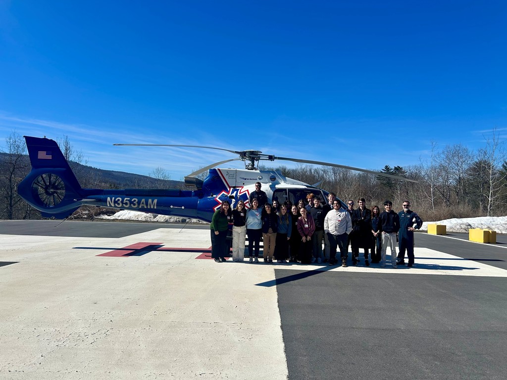 Group of students and pilot in front of a helicopter