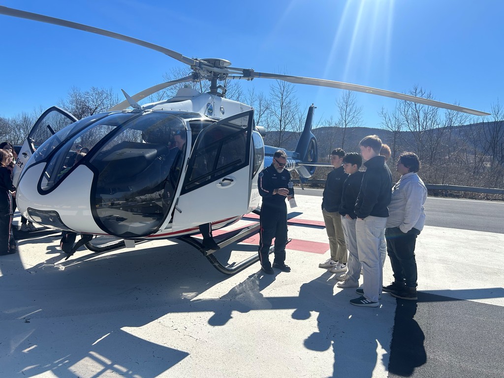 Helicopter pilot standing outside the chopper speaking with 5 students