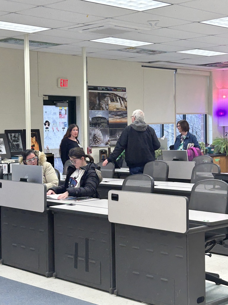 Students, adults, and instructor in the Visual Communications classroom with computers