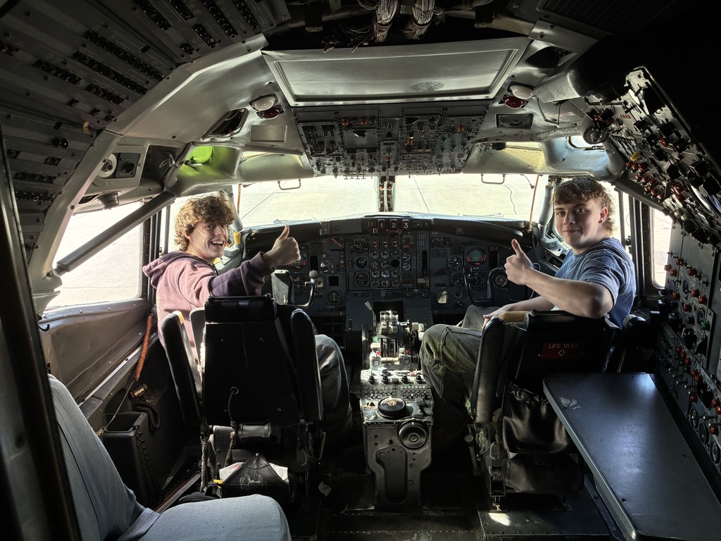 Two students giving thumbs up in a cockpit simulator