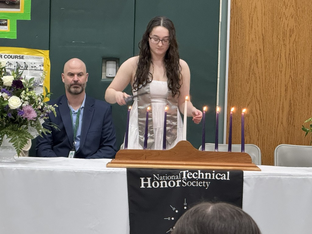 A student lighting the 7th candle representing the pillars of NTHS. A staff member is in the background.