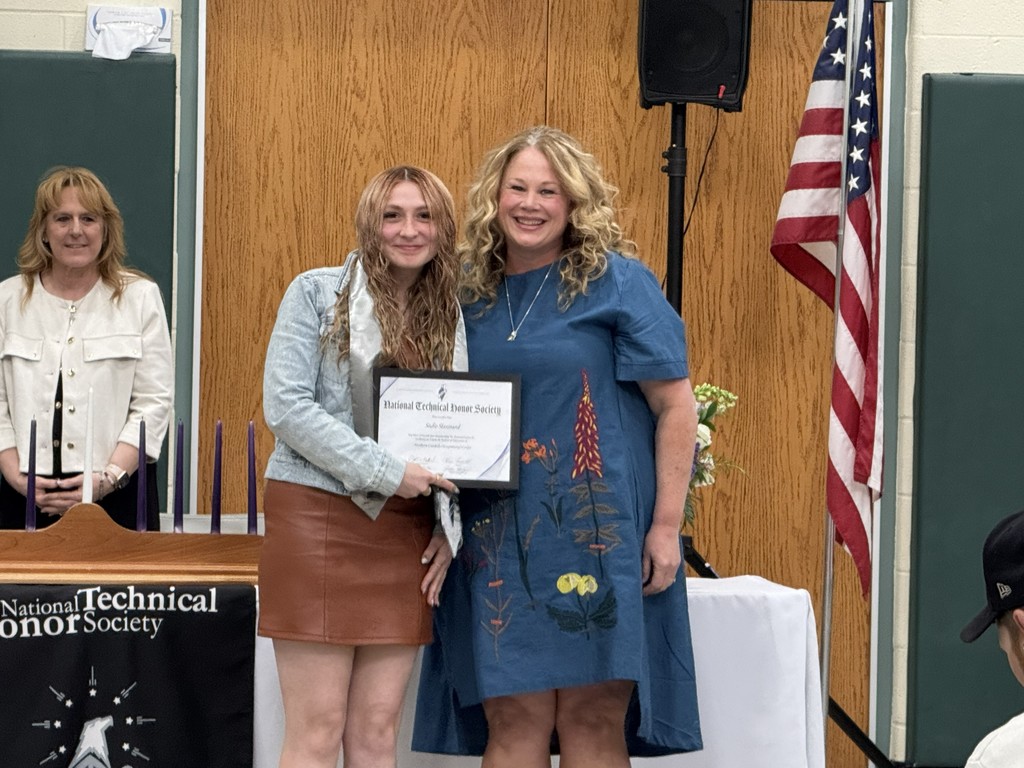 A newly inducted student holding their certificate is posing with their instructor.