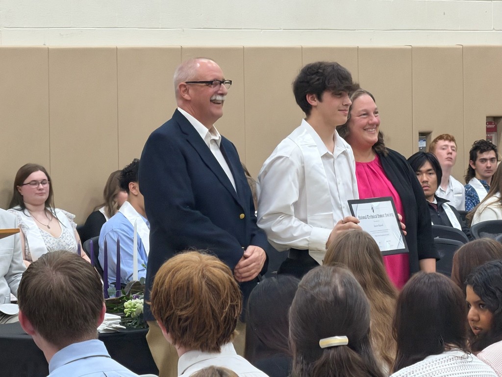 an instructor, student holding a certificate, and the building principal posing and smiling.