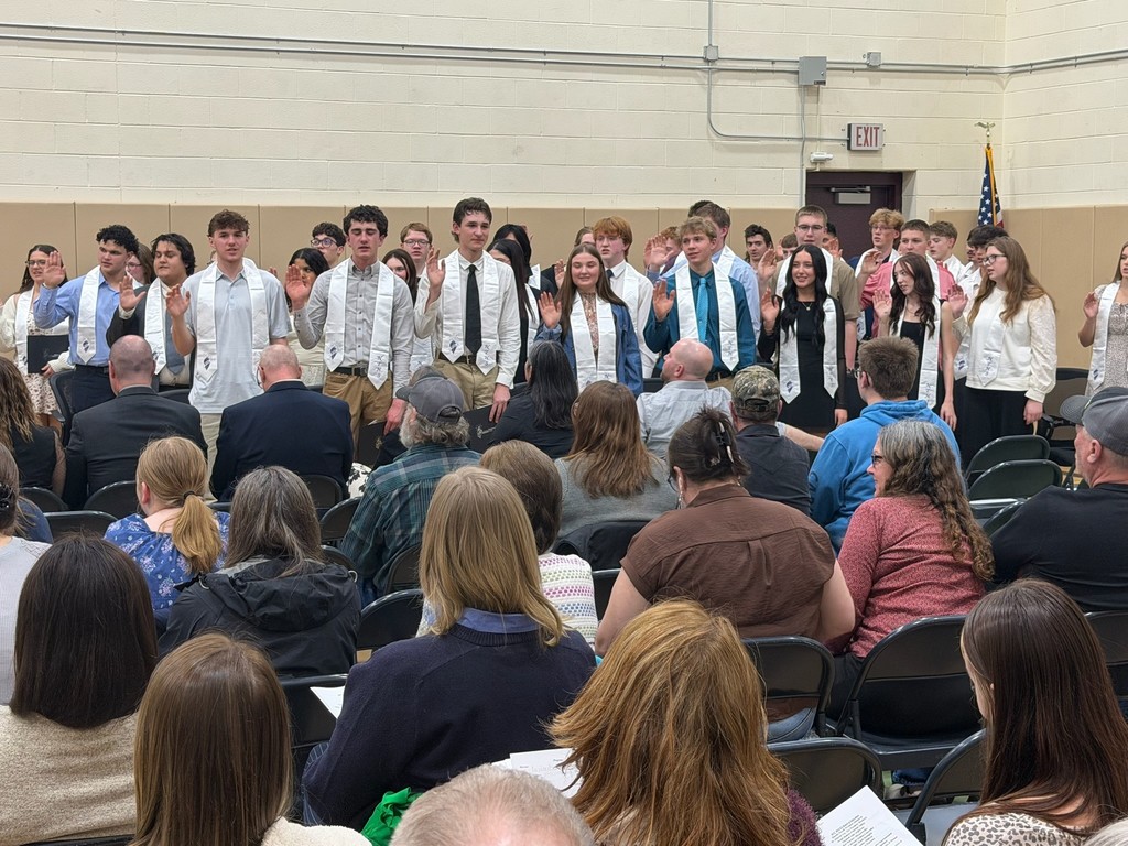 Large group of students with their hands up taking the NTHS oath.