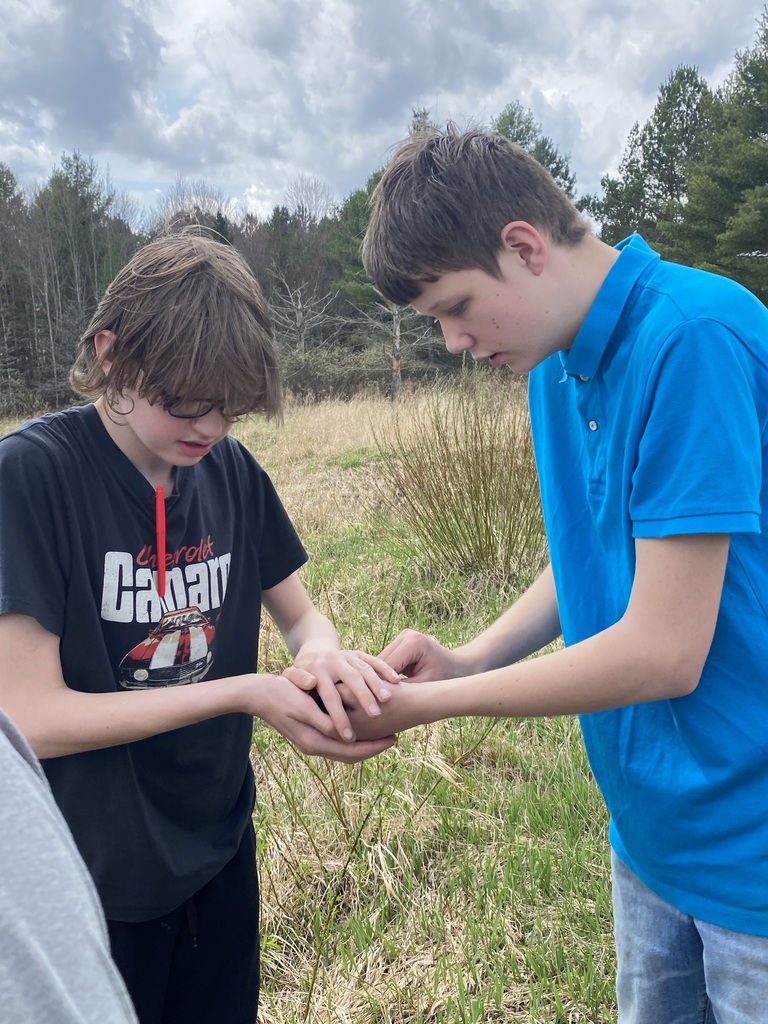 Two students with their hands cupped to keep from dropping something.