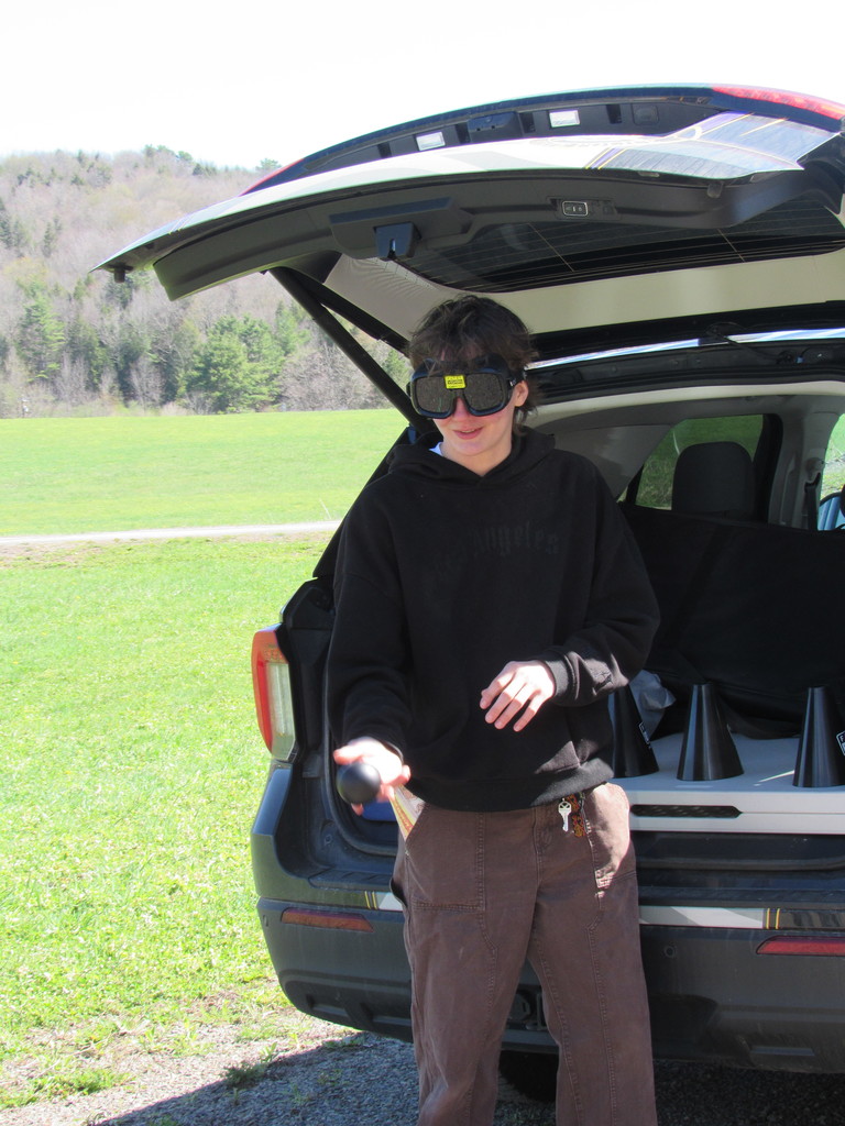 A high school student standing at the trunk of a car with goggles on